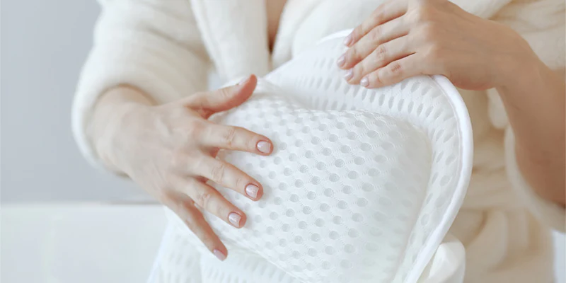 Frau hält das weiße, ergonomische Badewannenkissen L von vesta+ mit strukturiertem Stoff und Saugnäpfen für optimalen Komfort und Halt in der Badewanne.