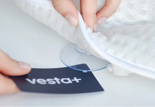 Detailaufnahme eines weißen Badewannenkissens von vesta+ mit Saugnäpfen zur sicheren Befestigung und vesta+ Logo.